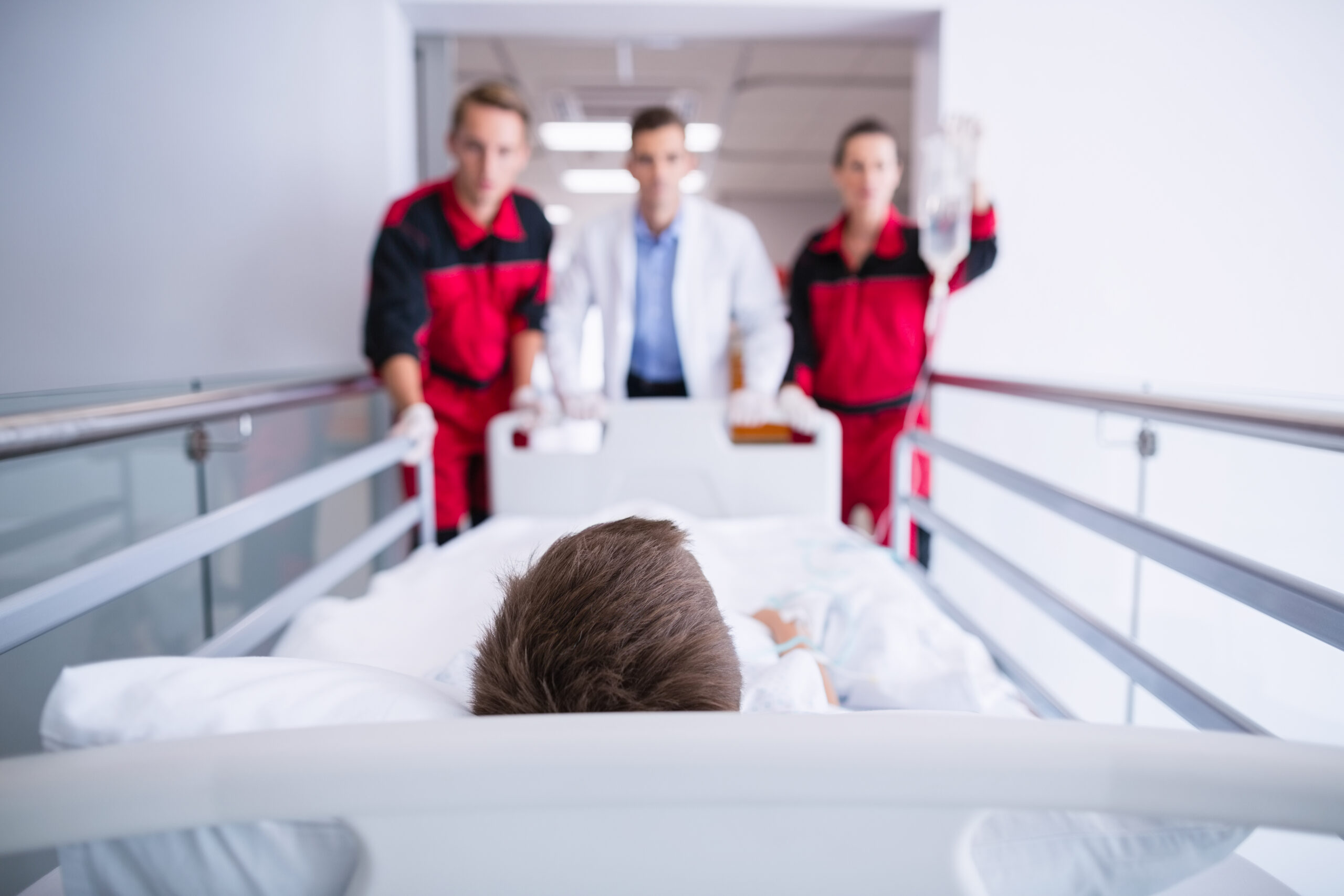 Doctors pushing emergency stretcher bed in corridor at hospital
